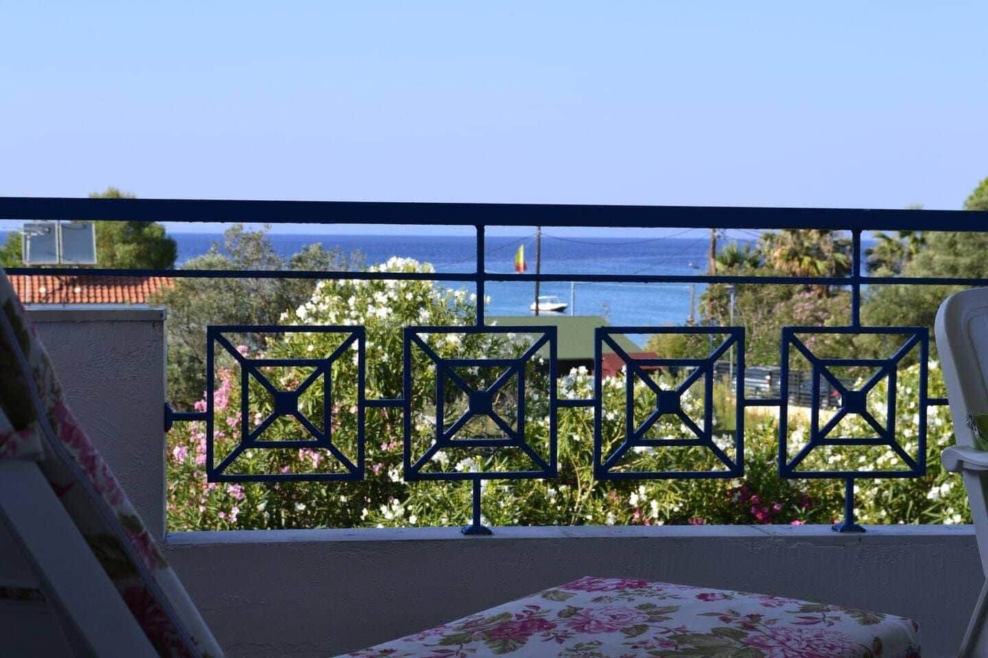 Luxury Greek beachfront townhouse with white walls and sea view from a sunlit balcony overlooking turquoise water