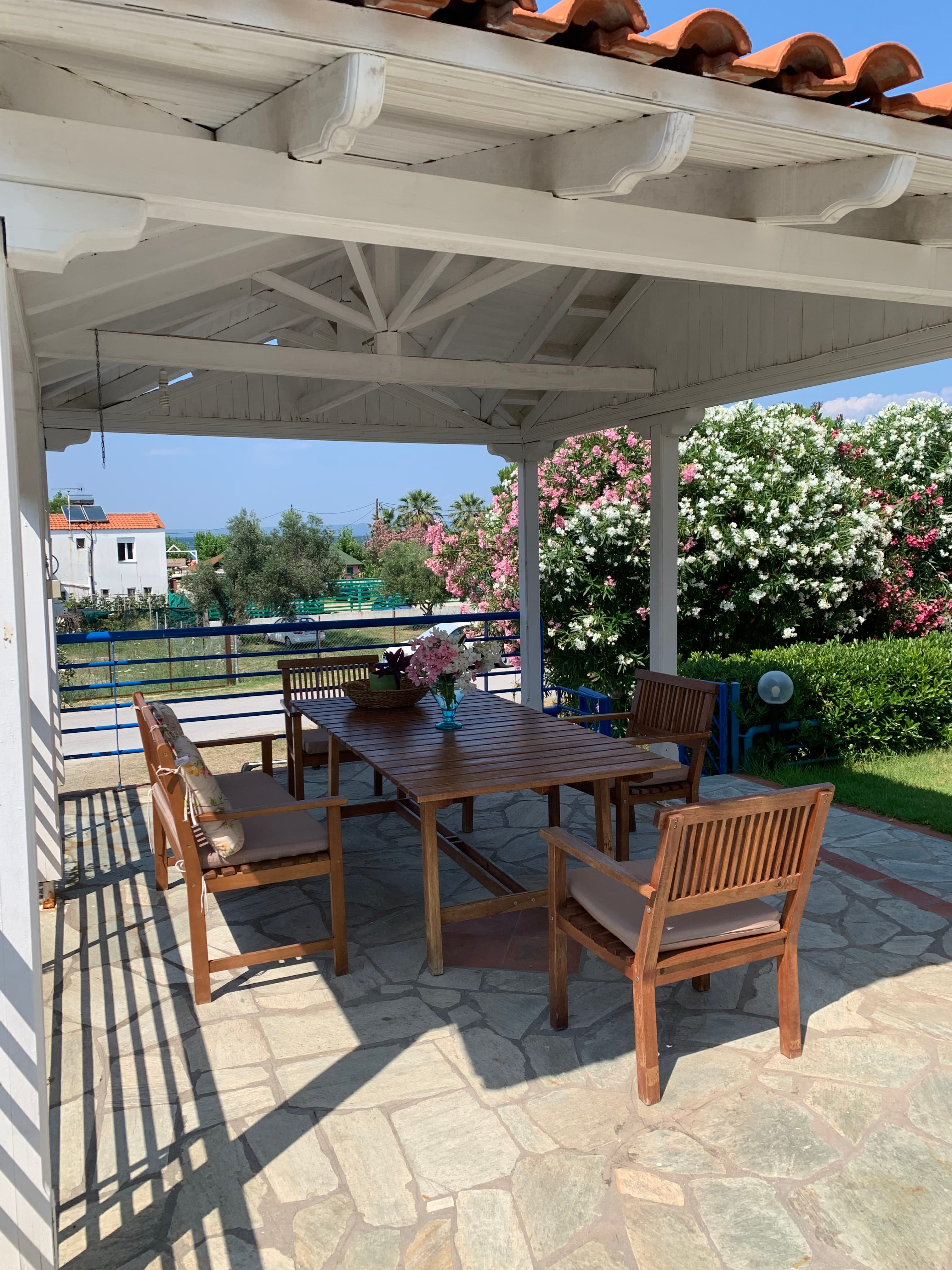 Outdoor dining table set for lunch in a lush green Greek garden with sea breeze