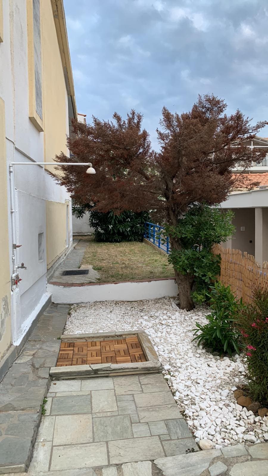 Close up of a sunlit outdoor shower with stone walls and Mediterranean plants